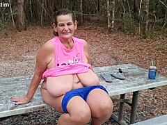Rijpe vrouw stript en urineert in het openbaar