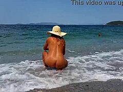 Érett nő kinyújtott mellbimbópiercingekkel és többszörös puncipiercigekkel a tengerparton