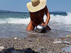 Reife Frau mit gedehnten Nippelpiercings und mehreren Muschipiercing am Strand