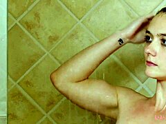 La modella bruna attraente si fa il bagno in una doccia calda