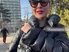 Een beeldschone vrouw laat haar grote borsten zien tijdens een wandeling in een park